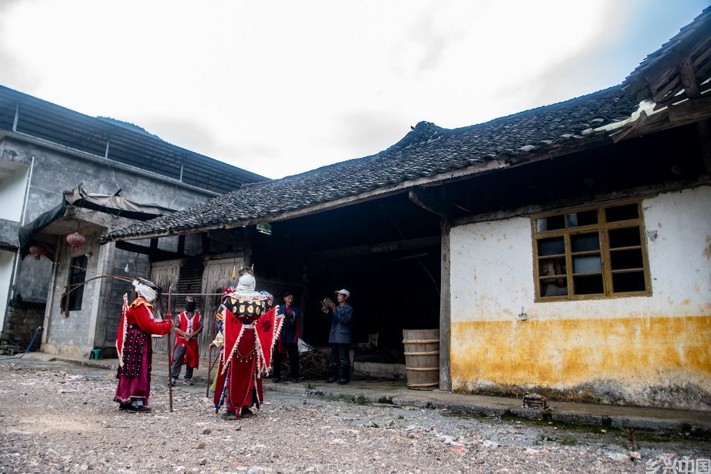 5月16日，在稻田旁的一间老屋前，戏班子成员在登台前熟悉表演站位。