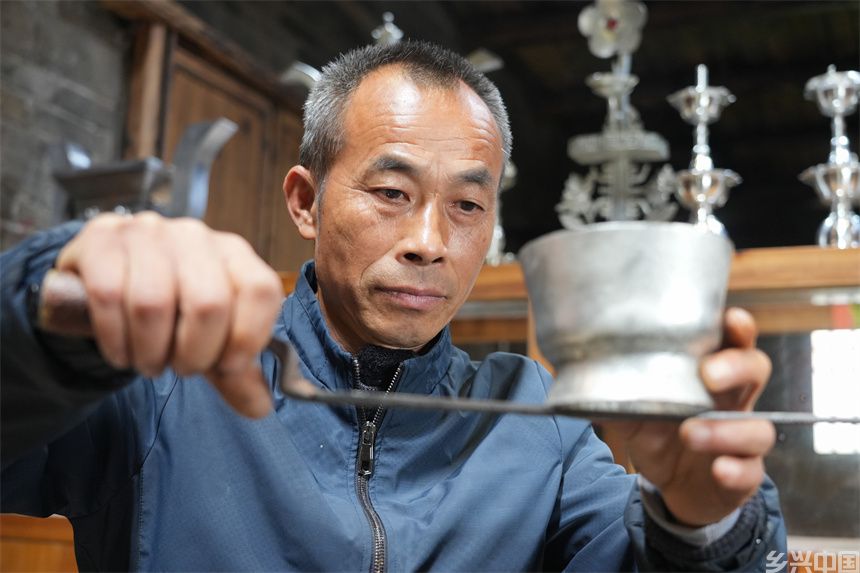 国家级非遗锡雕（莲花打锡）代表性传承人刘建强在检查锡雕的平整度。人民网 孔文进摄