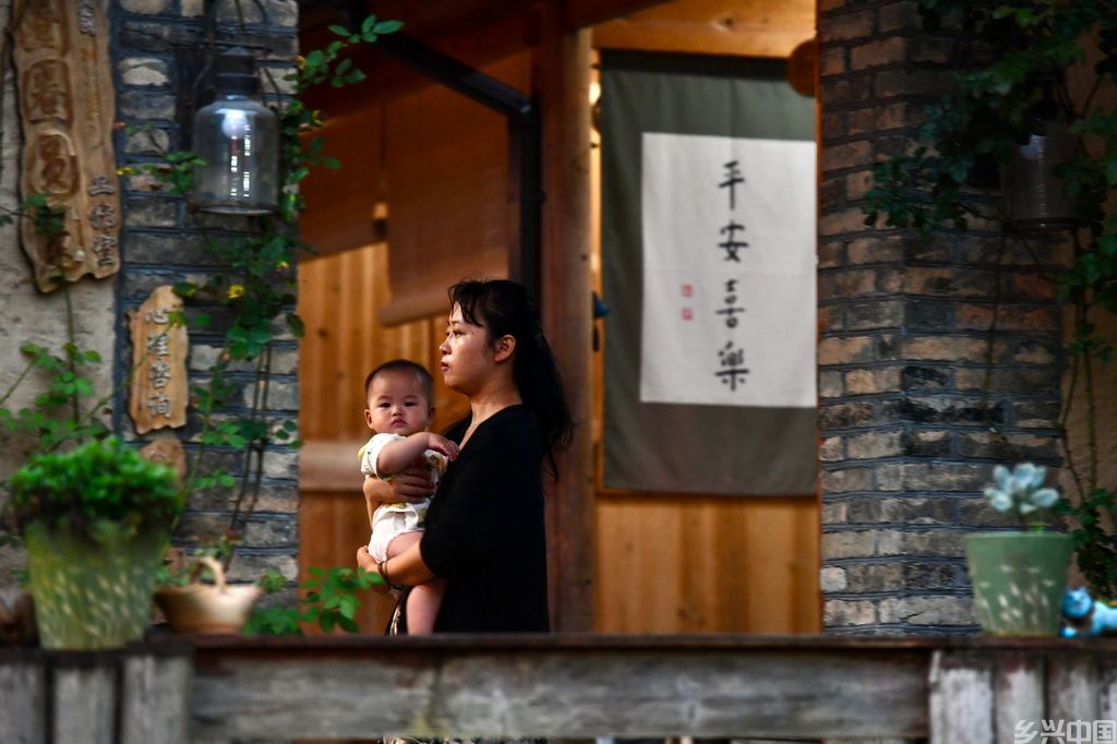 8月29日，一位龙潭村“新村民”抱着孩子走在自己经营的民宿内。