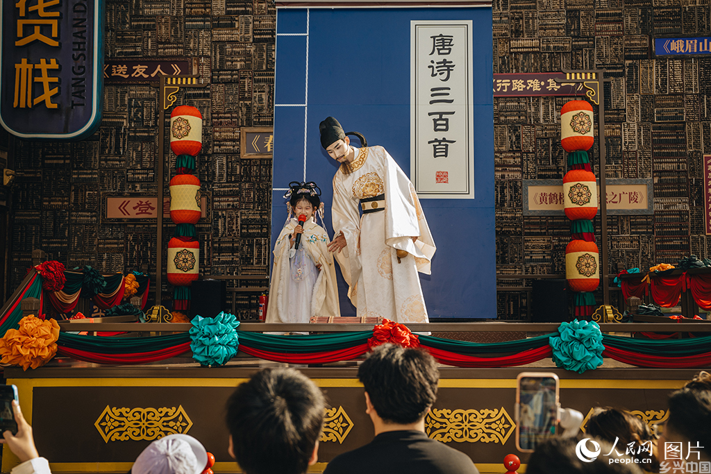 2026年5月18日,河北唐山河头老街的NPC演员“李白”正与小游客吟诗互动。人民网记者 商帆摄
